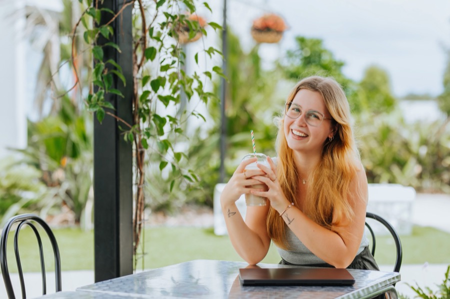 A business owner at a cafe table surrounded by plants